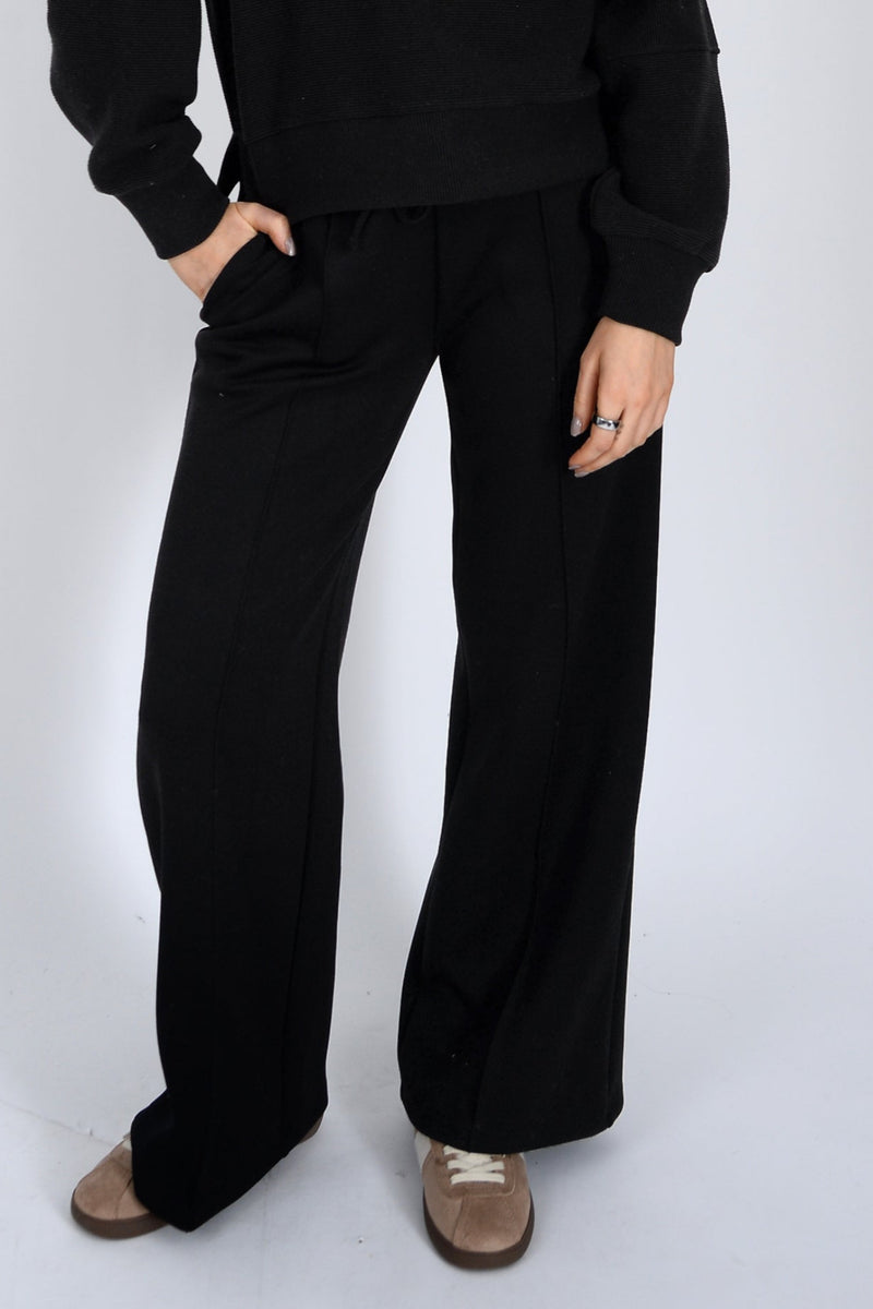 Person wearing black pants and a black top on a white background