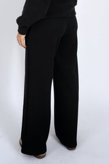Person wearing black wide-leg pants on a white background
