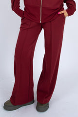 Maroon tracksuit worn by a person on a white background