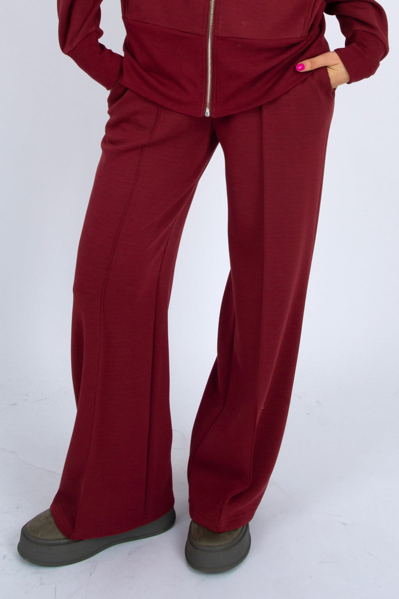 Maroon tracksuit worn by a person on a white background