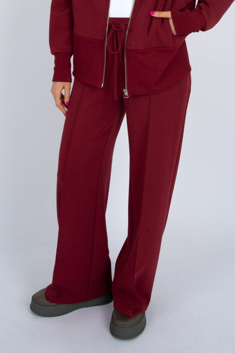 Person wearing a burgundy tracksuit on a white background