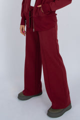 Person wearing a burgundy tracksuit with wide-leg pants on a white background