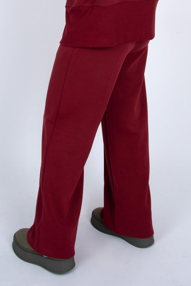 Burgundy pants worn by a person on a white background