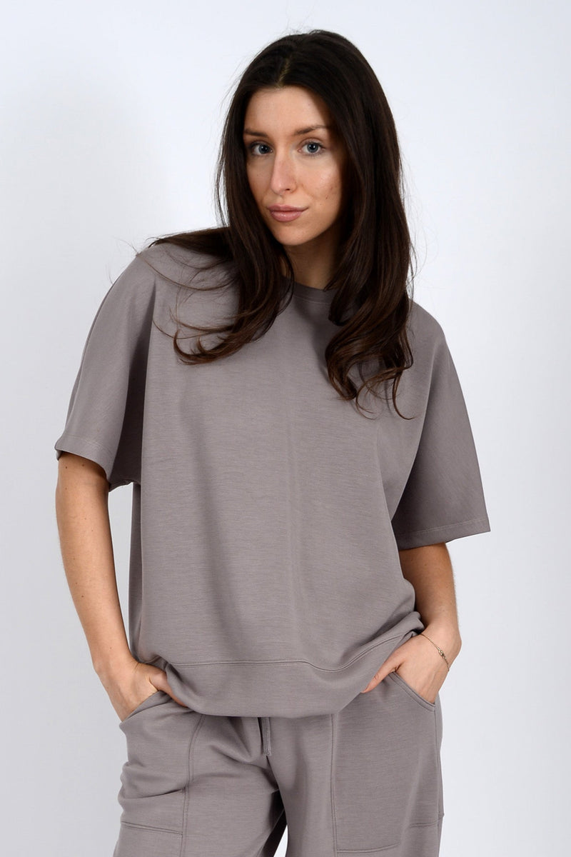 Woman wearing a gray outfit against a white background