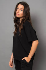 Woman wearing a black outfit against a gray background
