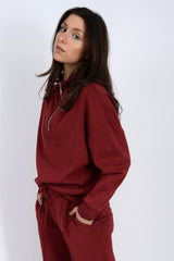 Woman wearing a burgundy tracksuit against a white background.