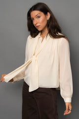 Woman wearing a cream blouse with a gray background
