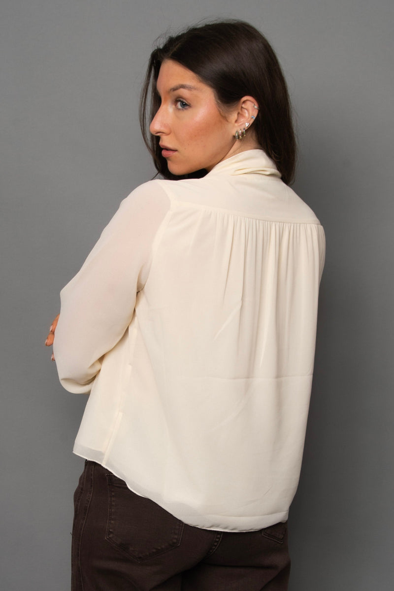 Woman wearing a cream blouse against a gray background