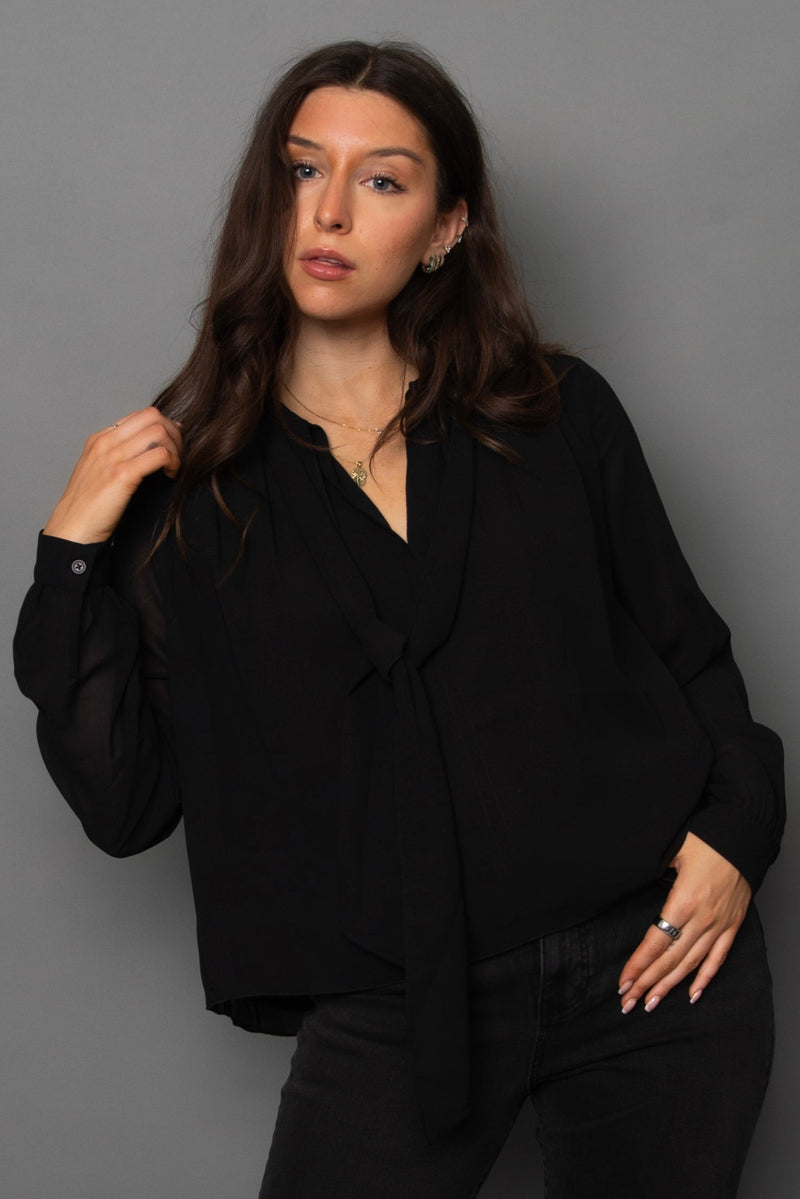 Woman wearing a black outfit against a gray background