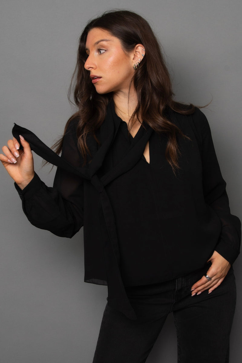 Woman wearing a black outfit against a gray background