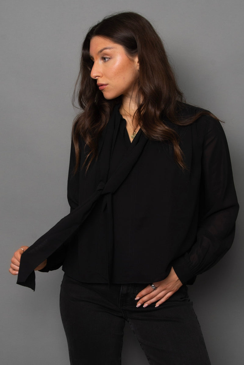 Woman wearing a black blouse against a gray background